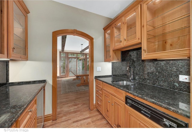 kitchen with dishwasher, dark stone countertops, light wood-type flooring, and sink