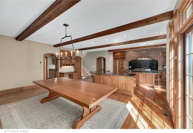 dining space with beamed ceiling and light wood-type flooring