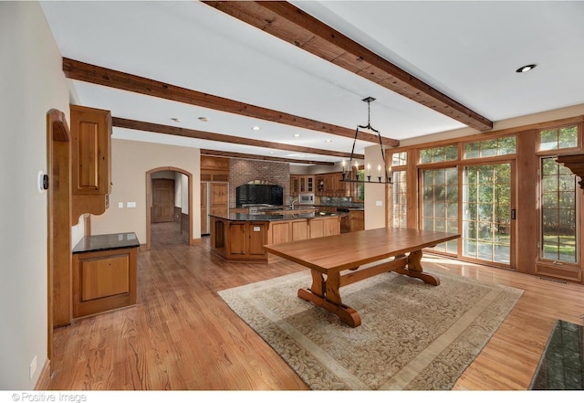 dining room with beamed ceiling, light wood-type flooring, and a chandelier