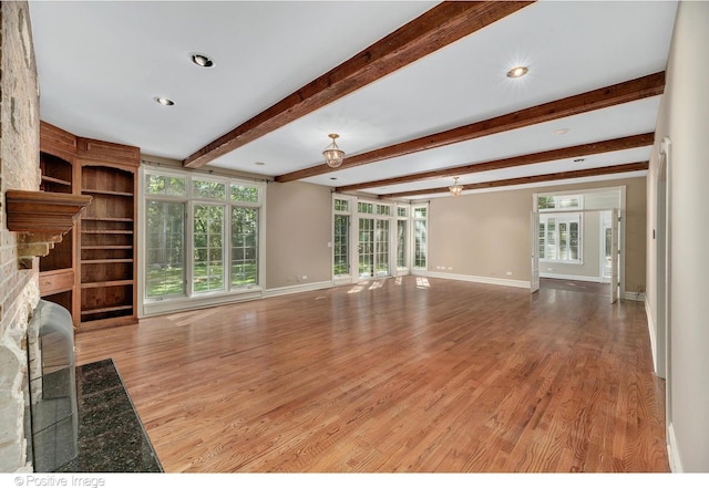 unfurnished living room with beam ceiling, light hardwood / wood-style floors, and a fireplace