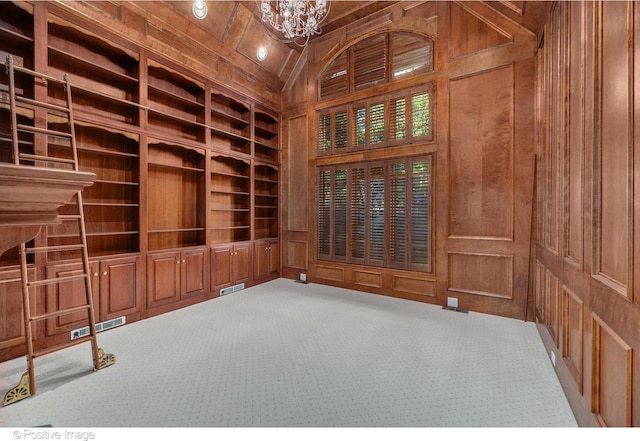 interior space featuring carpet, wooden walls, high vaulted ceiling, built in features, and a notable chandelier