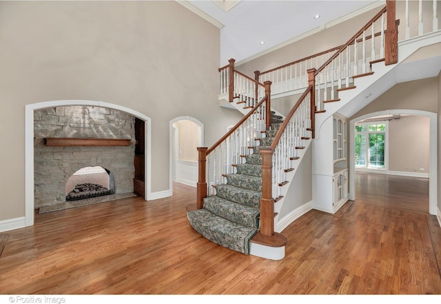 staircase with a fireplace, hardwood / wood-style flooring, and crown molding