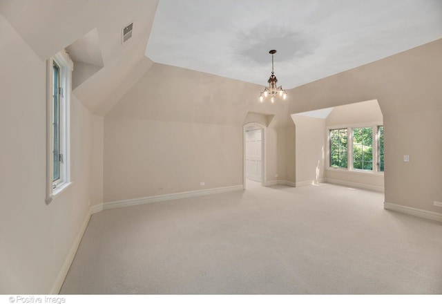 additional living space with a chandelier, light carpet, and vaulted ceiling