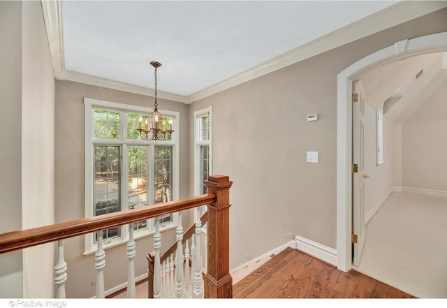 hall with crown molding, hardwood / wood-style floors, and an inviting chandelier