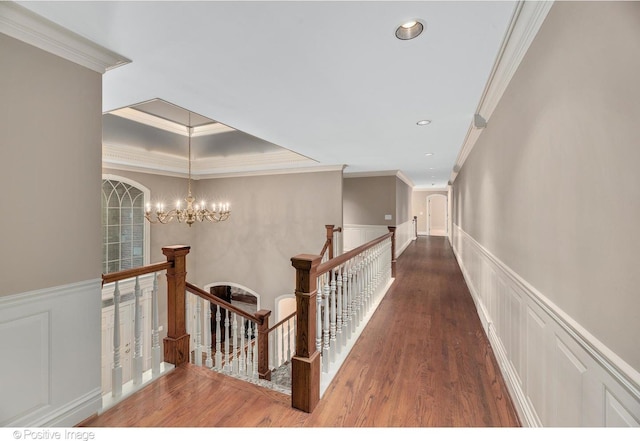 corridor with hardwood / wood-style flooring, an inviting chandelier, and crown molding