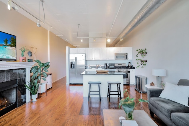 kitchen featuring a center island, a breakfast bar area, a fireplace, white cabinets, and appliances with stainless steel finishes