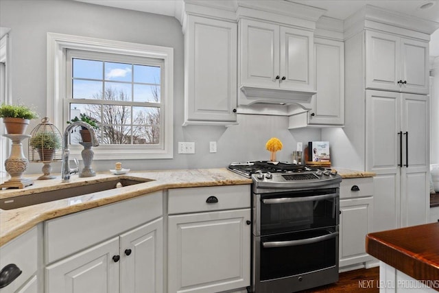 kitchen featuring gas stove, white cabinetry, sink, and custom range hood