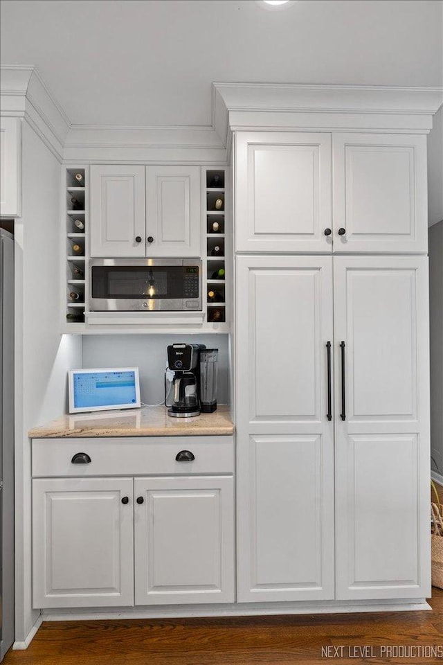 bar featuring white cabinets, crown molding, dark hardwood / wood-style flooring, and stainless steel appliances