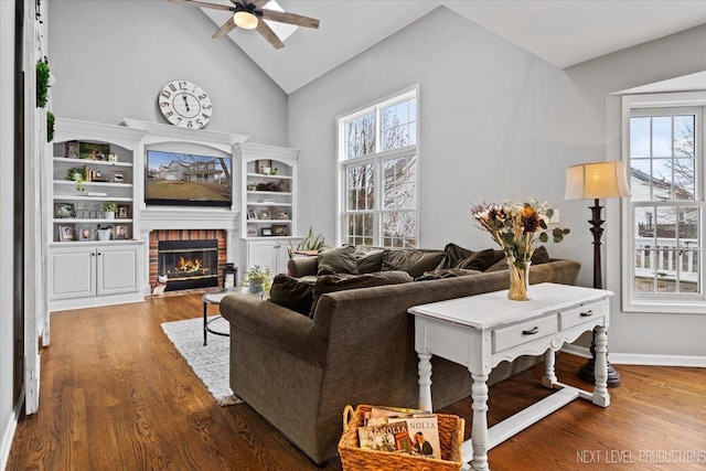 living room featuring ceiling fan, high vaulted ceiling, dark wood-type flooring, and a brick fireplace