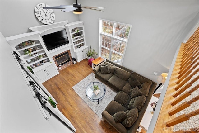 living room with ceiling fan, wood-type flooring, and a fireplace