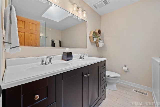 bathroom featuring a skylight, vanity, and toilet