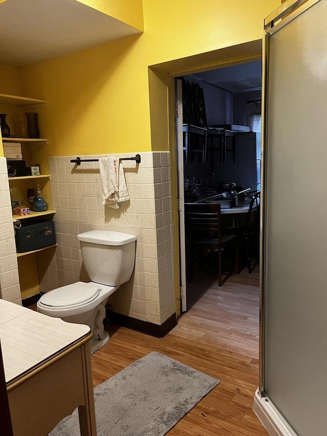 bathroom with wood-type flooring, tile walls, and toilet