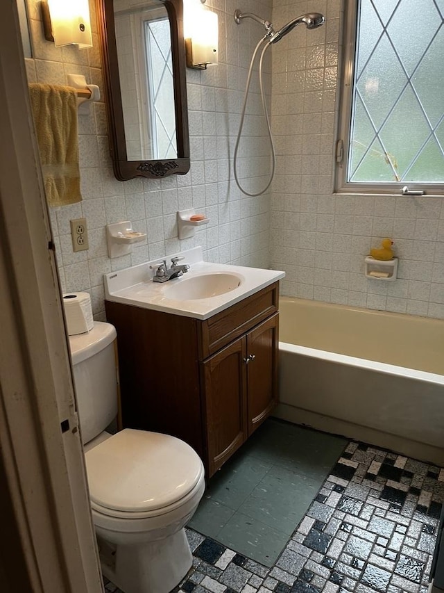 full bathroom with vanity, tiled shower / bath combo, tile walls, and toilet