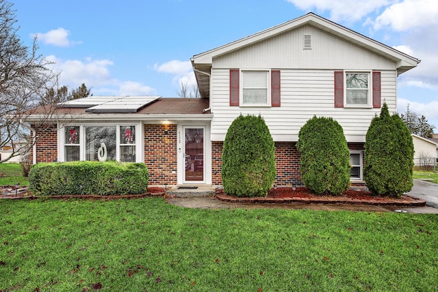 tri-level home featuring solar panels and a front yard