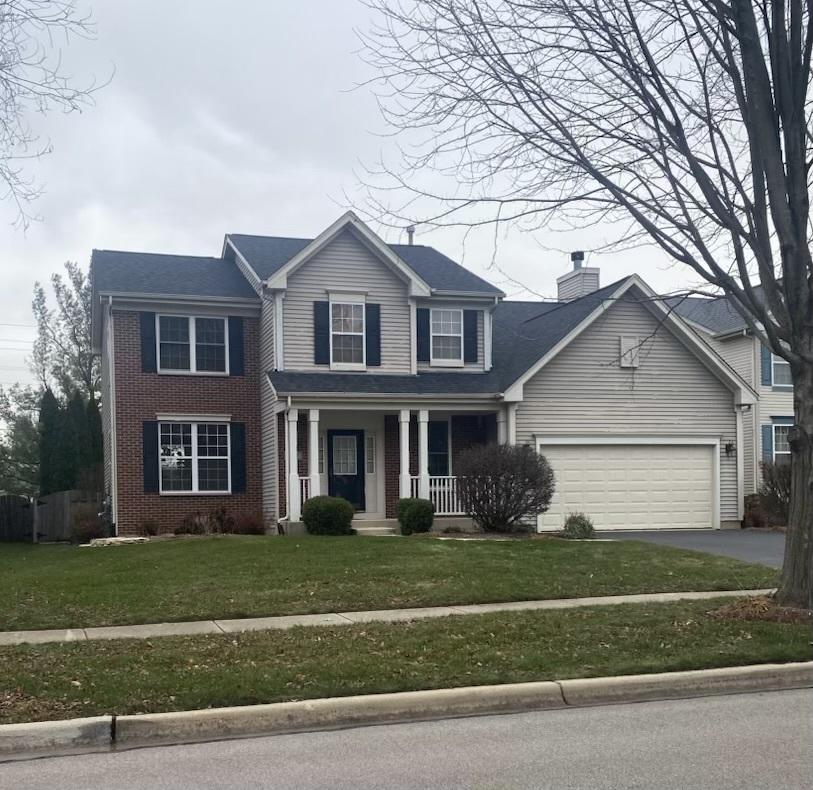 view of front of home featuring covered porch, a garage, and a front lawn