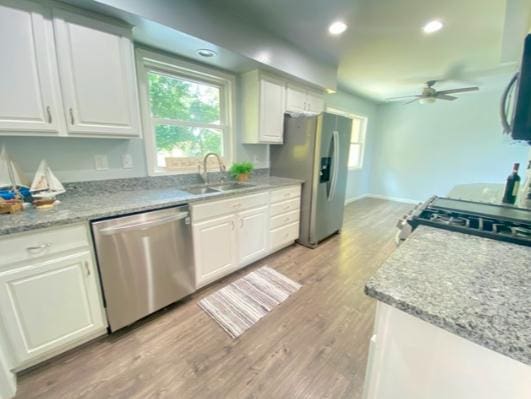 kitchen with sink, ceiling fan, light hardwood / wood-style floors, white cabinetry, and stainless steel appliances