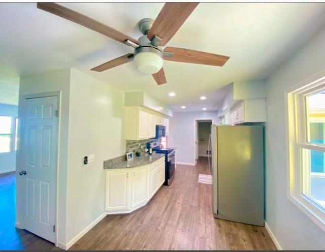 kitchen featuring white cabinets, hardwood / wood-style floors, stainless steel appliances, and a healthy amount of sunlight