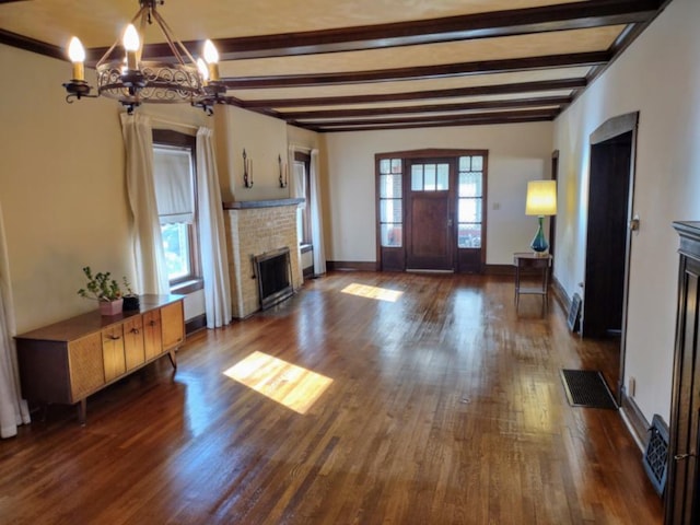 unfurnished living room featuring beamed ceiling, dark wood-type flooring, a notable chandelier, and a brick fireplace