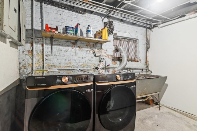 washroom featuring washing machine and clothes dryer, electric panel, and sink