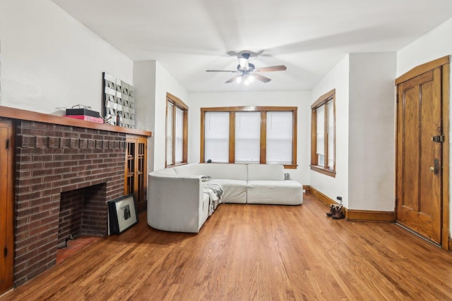 living room with hardwood / wood-style floors, a brick fireplace, and ceiling fan