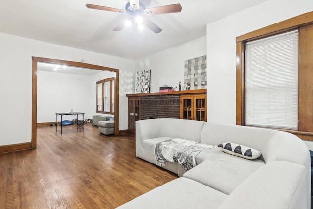 living room featuring hardwood / wood-style floors, ceiling fan, and a fireplace