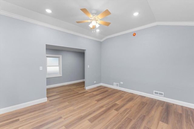 empty room featuring ceiling fan, light wood-type flooring, crown molding, and vaulted ceiling