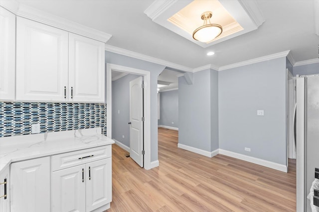 kitchen with crown molding, light stone countertops, tasteful backsplash, white fridge, and white cabinetry