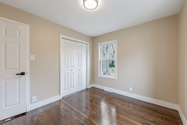 unfurnished bedroom featuring dark hardwood / wood-style flooring and a closet