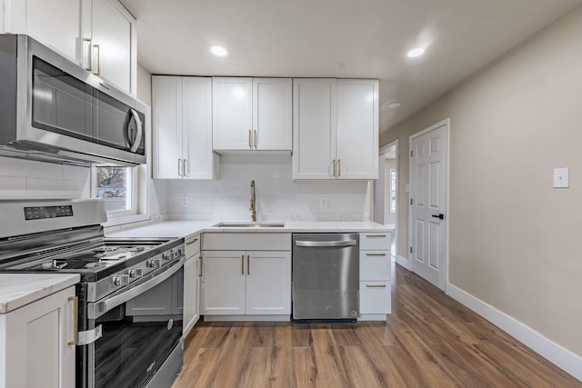 kitchen with hardwood / wood-style floors, white cabinetry, sink, and stainless steel appliances