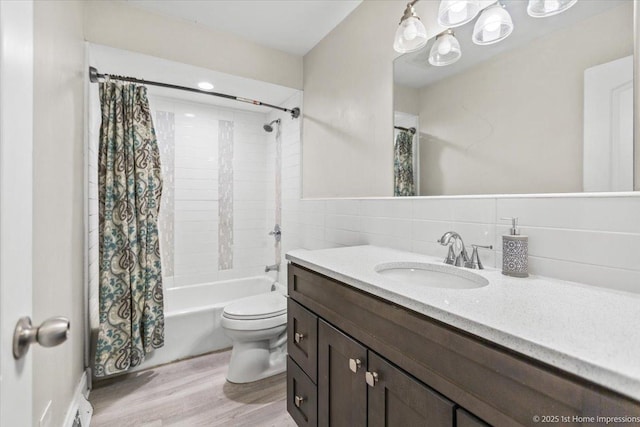 full bathroom featuring toilet, decorative backsplash, shower / tub combo with curtain, vanity, and tile walls