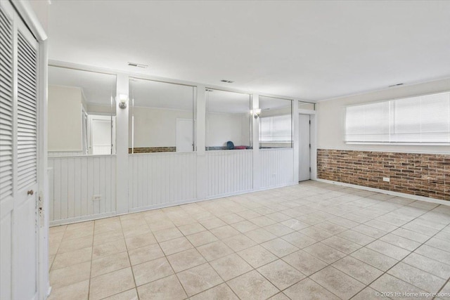 tiled empty room featuring brick wall