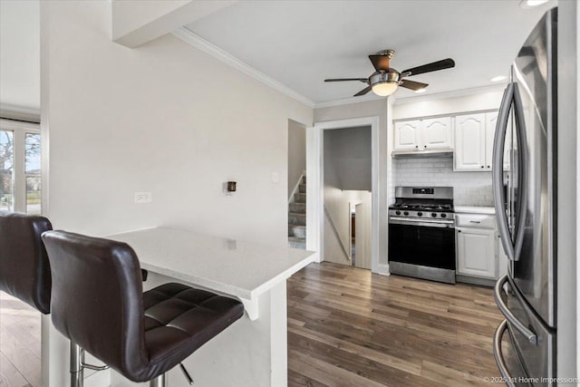 kitchen featuring backsplash, a breakfast bar area, dark hardwood / wood-style flooring, white cabinetry, and stainless steel appliances