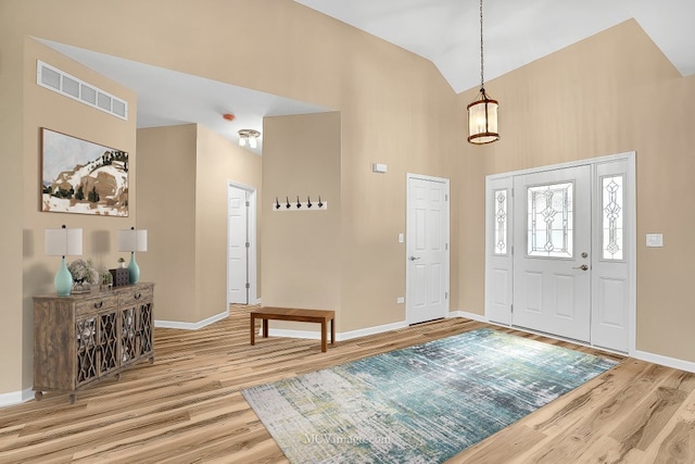 foyer entrance with hardwood / wood-style floors and high vaulted ceiling