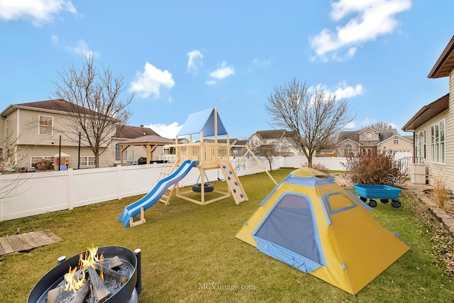 view of playground featuring a lawn and a fire pit