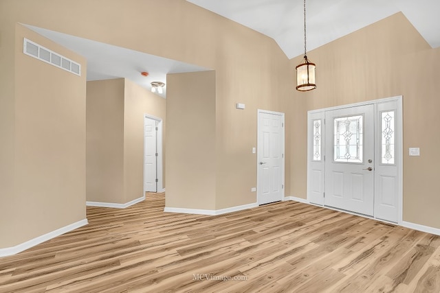 foyer entrance with light hardwood / wood-style floors and high vaulted ceiling