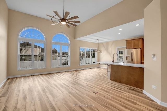 kitchen featuring stainless steel fridge with ice dispenser, sink, pendant lighting, and light hardwood / wood-style floors