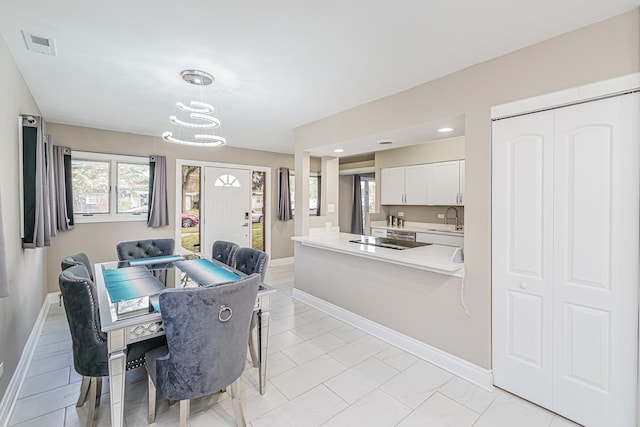 dining space with light tile patterned flooring, a notable chandelier, and sink