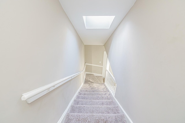 stairs featuring a skylight and carpet floors