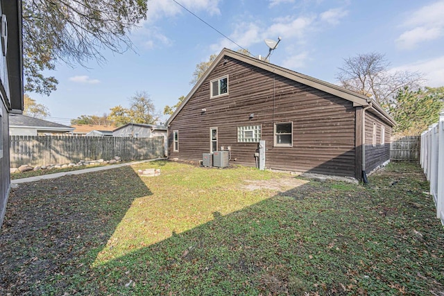 back of property featuring central air condition unit and a yard