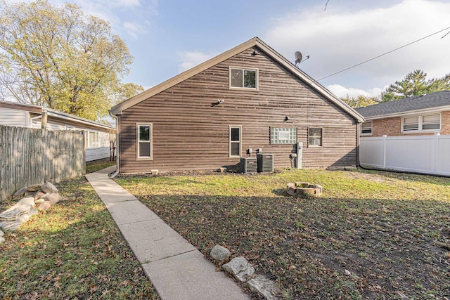 rear view of house featuring a lawn and central air condition unit