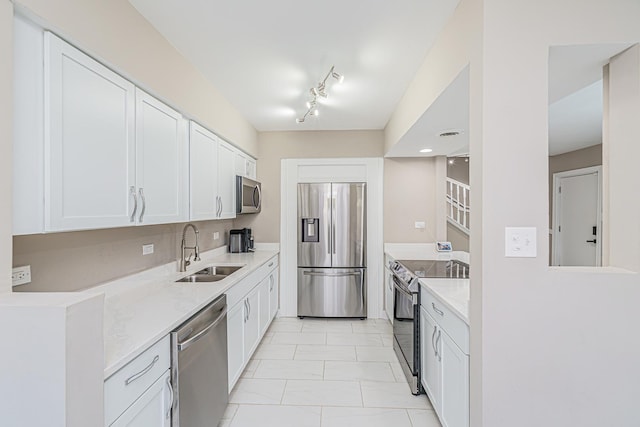 kitchen with light stone counters, sink, white cabinetry, and stainless steel appliances