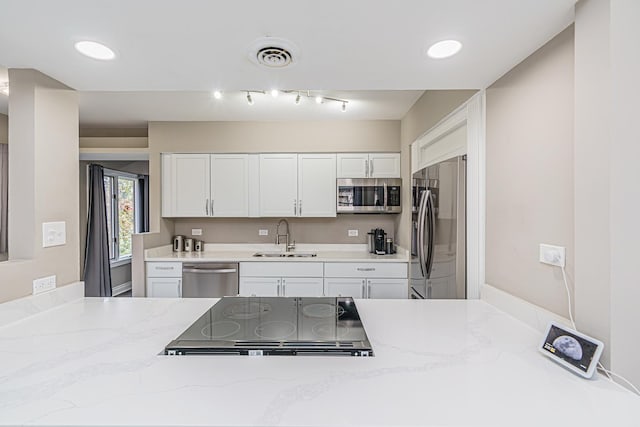 kitchen featuring white cabinets, stainless steel appliances, light stone countertops, and sink