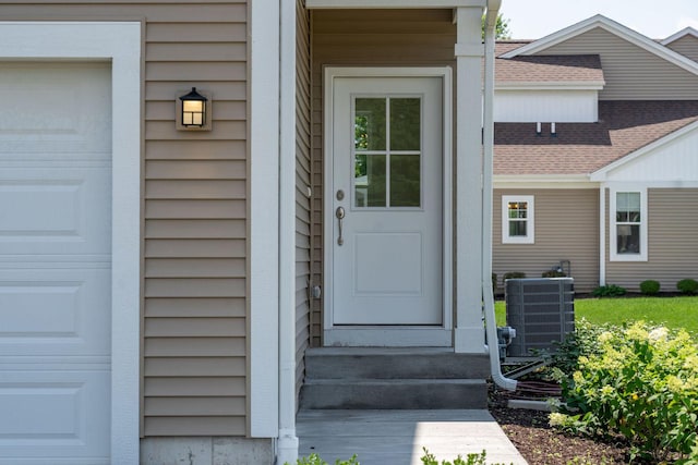 view of exterior entry featuring a garage and central AC