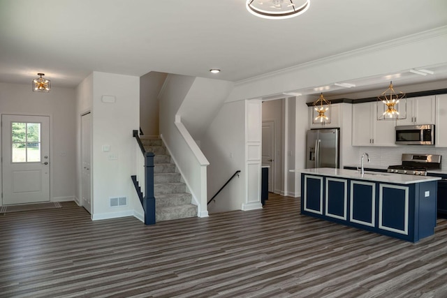 kitchen featuring pendant lighting, a kitchen island with sink, white cabinets, blue cabinets, and stainless steel appliances