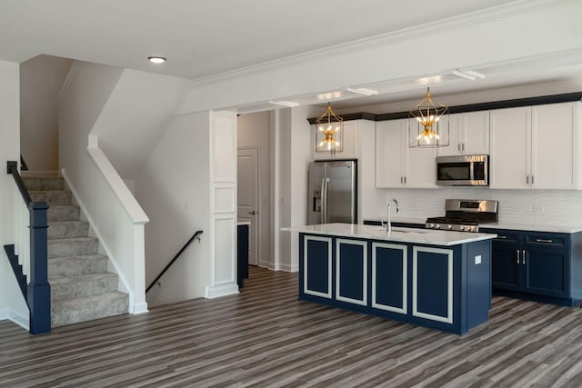 kitchen featuring pendant lighting, blue cabinets, an island with sink, white cabinetry, and stainless steel appliances