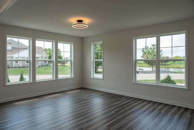 unfurnished room with dark hardwood / wood-style floors and a water view