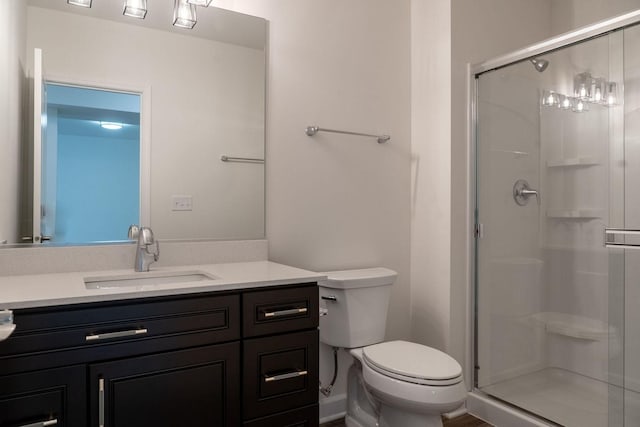 bathroom featuring vanity, an enclosed shower, and toilet