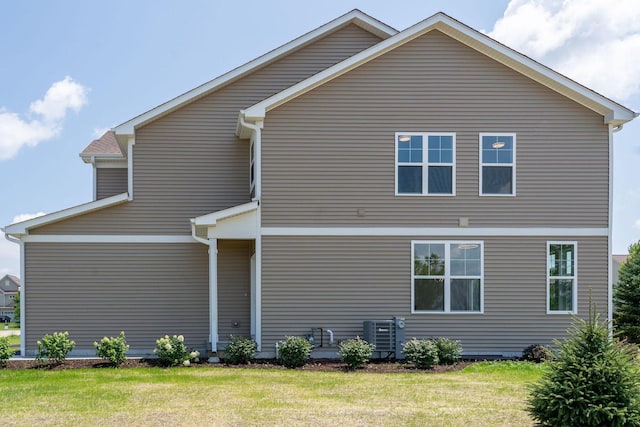 rear view of property with central AC and a lawn