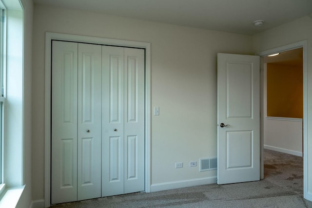 unfurnished bedroom featuring light colored carpet and a closet