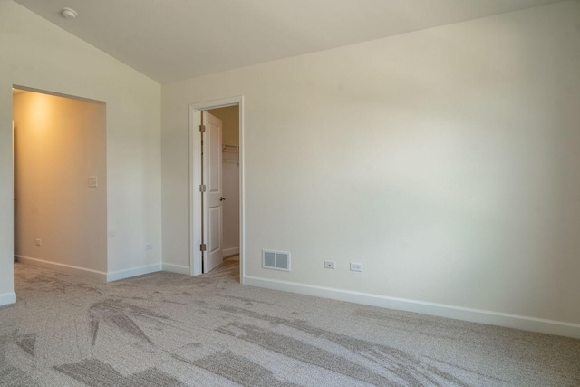 empty room with light colored carpet and lofted ceiling